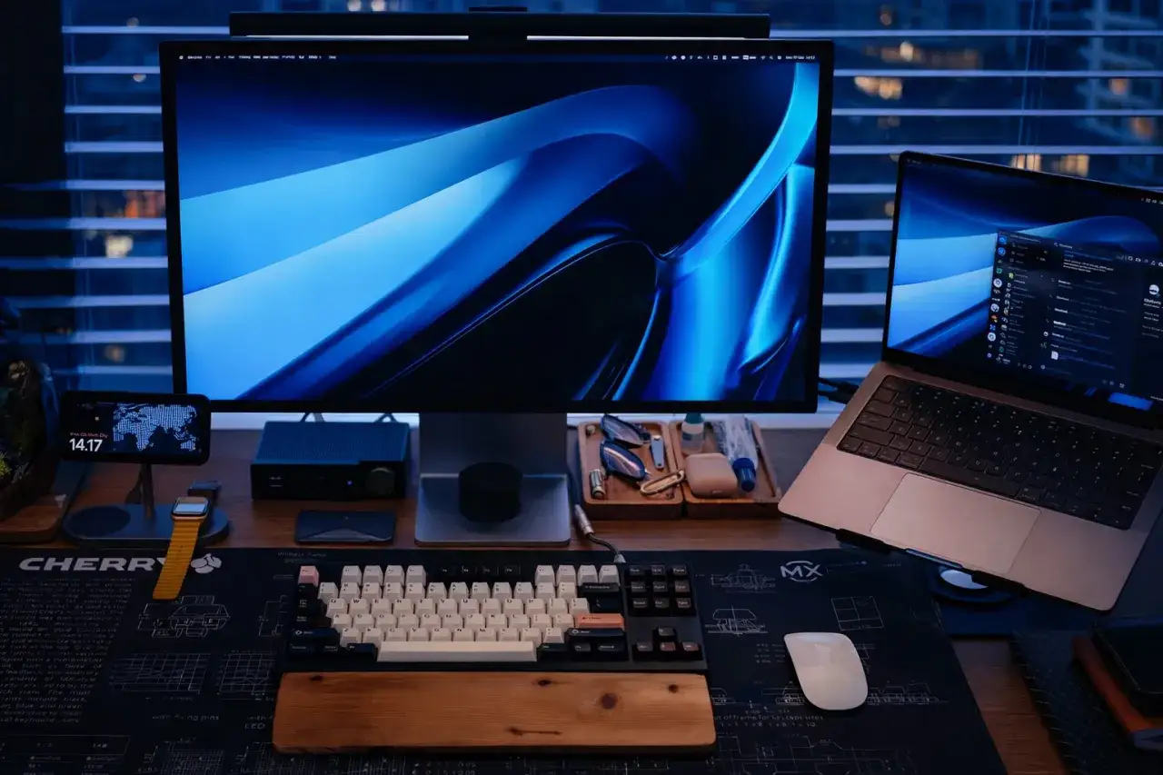 Ustawienie głównego monitora w tym stanowisku pracy z dwoma ekranami jest kluczowe. Widoczny jest duży monitor z niebieskim tłem i laptop.