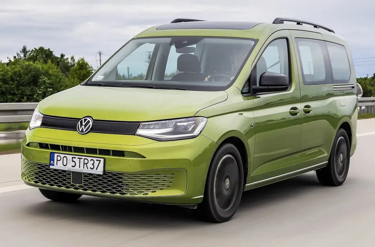 Zielony Volkswagen Caddy na drodze, z widocznym logo i tablicą rejestracyjną.