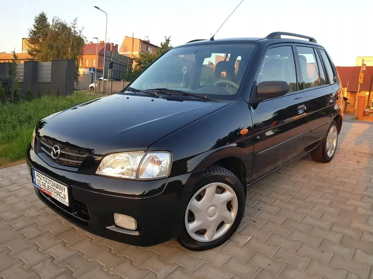 Czarna Mazda Demio na chodniku, gotowa do rejestracji.