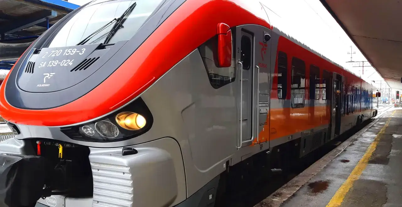 Nowoczesny pociąg Polregio z czerwono-szarym malowaniem stoi na peronie. Co to pr pociag? To środek transportu, który zabierze Cię w podróż.