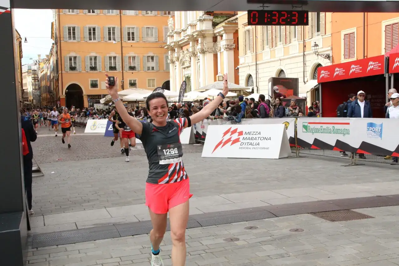 Donna festeggia al traguardo della Mezza Maratona d'Italia. La sua velocit&agrave; media maratona 42 km &egrave; stata eccellente!