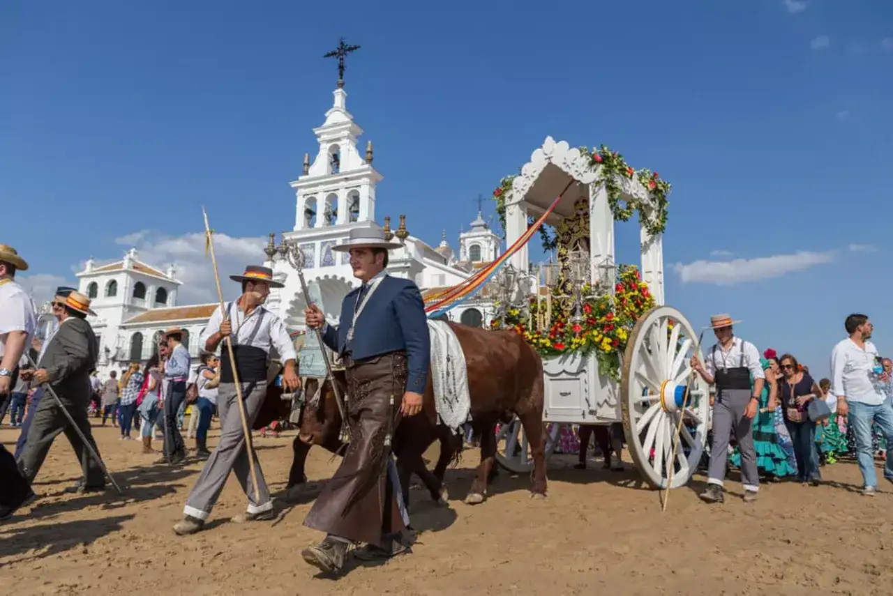 Procesión en El Rocío, con un carro adornado y bueyes. La historia del Rocío se vive en esta romería.
