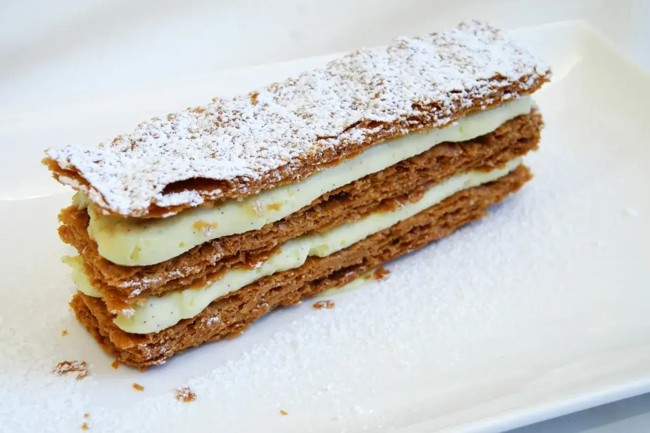 Un délicieux millefeuille, empilé de couches croustillantes et de crème pâtissière onctueuse, saupoudré de sucre glace.