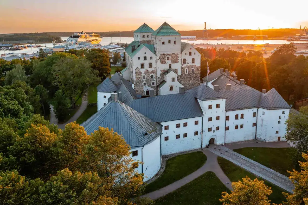 Zamek w Turku, najstarsze miasto w Finlandii, o zachodzie słońca. W tle port z wycieczkowcem.