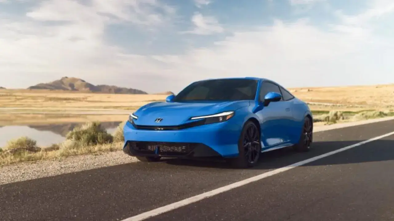La Honda Prelude 2026, un'auto sportiva blu brillante, sfreccia su una strada deserta con montagne sullo sfondo.