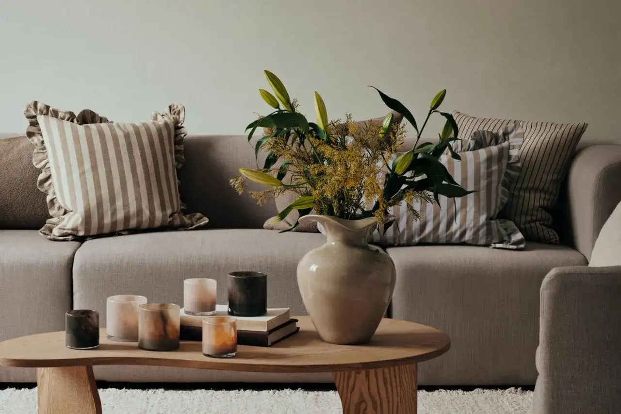 Gemütliches Sofa mit gestreiften Kissen und Blumenstrauß. So lässt sich das Sofa dekorieren, Kissen richtig kombinieren für ein harmonisches Bild.