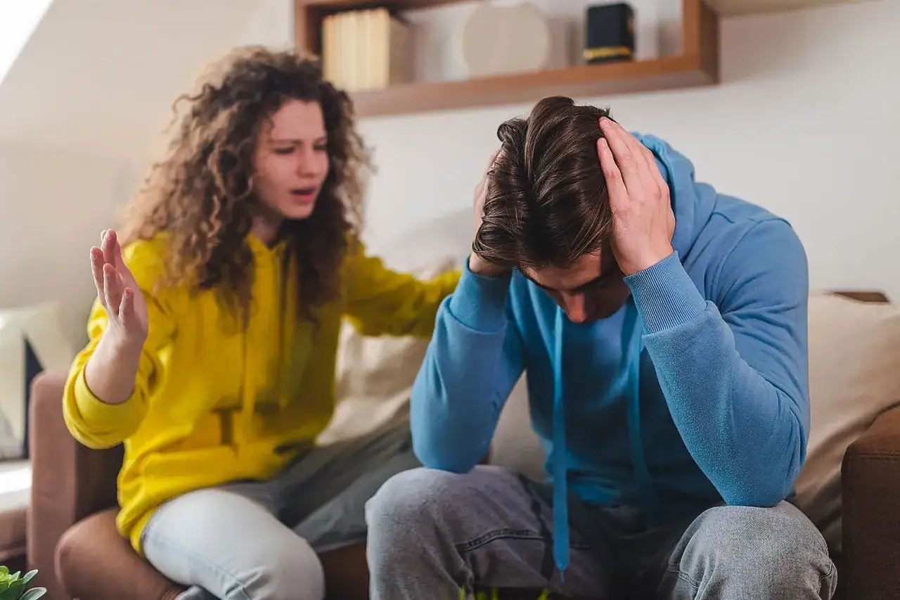 Ragazza con capelli ricci in felpa gialla parla con ragazzo in felpa blu, testa tra le mani, come chiudere una storia.