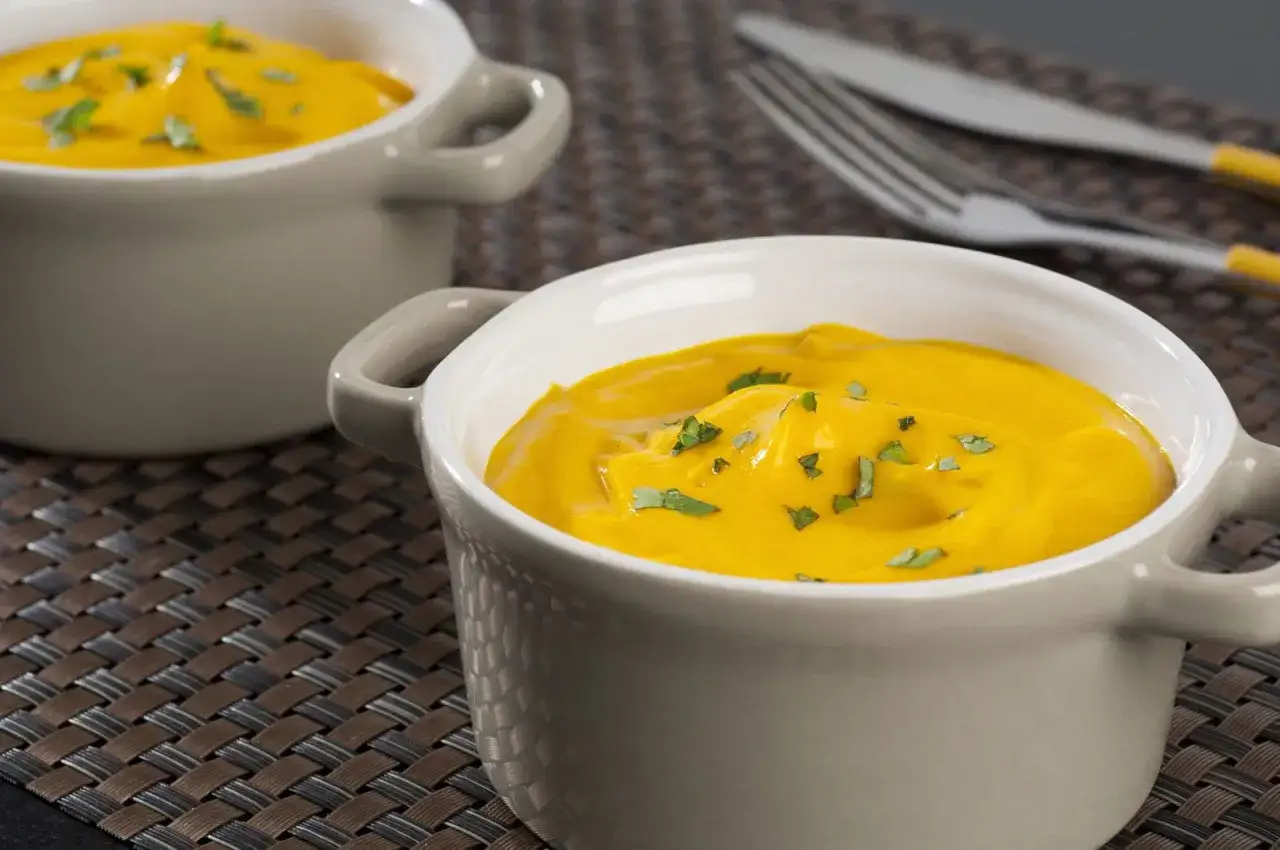 Deux bols de velouté de carotte, garni de persil frais, prêts à être dégustés.