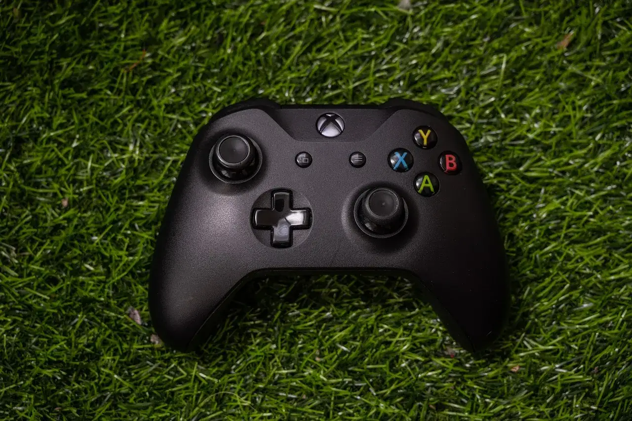 Czarny kontroler Xbox na zielonej trawie. Idealny do gier cross play Xbox PC, gdzie możesz grać ze znajomymi niezależnie od platformy.