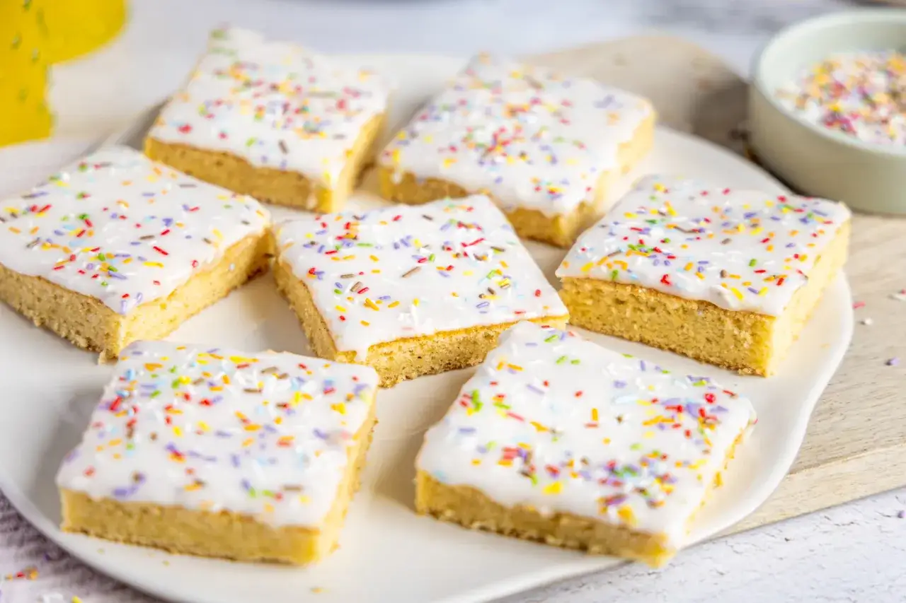 Leckere Stücke Fantakuchen, ein einfaches Tassenrezept, verziert mit weißer Glasur und bunten Streuseln.