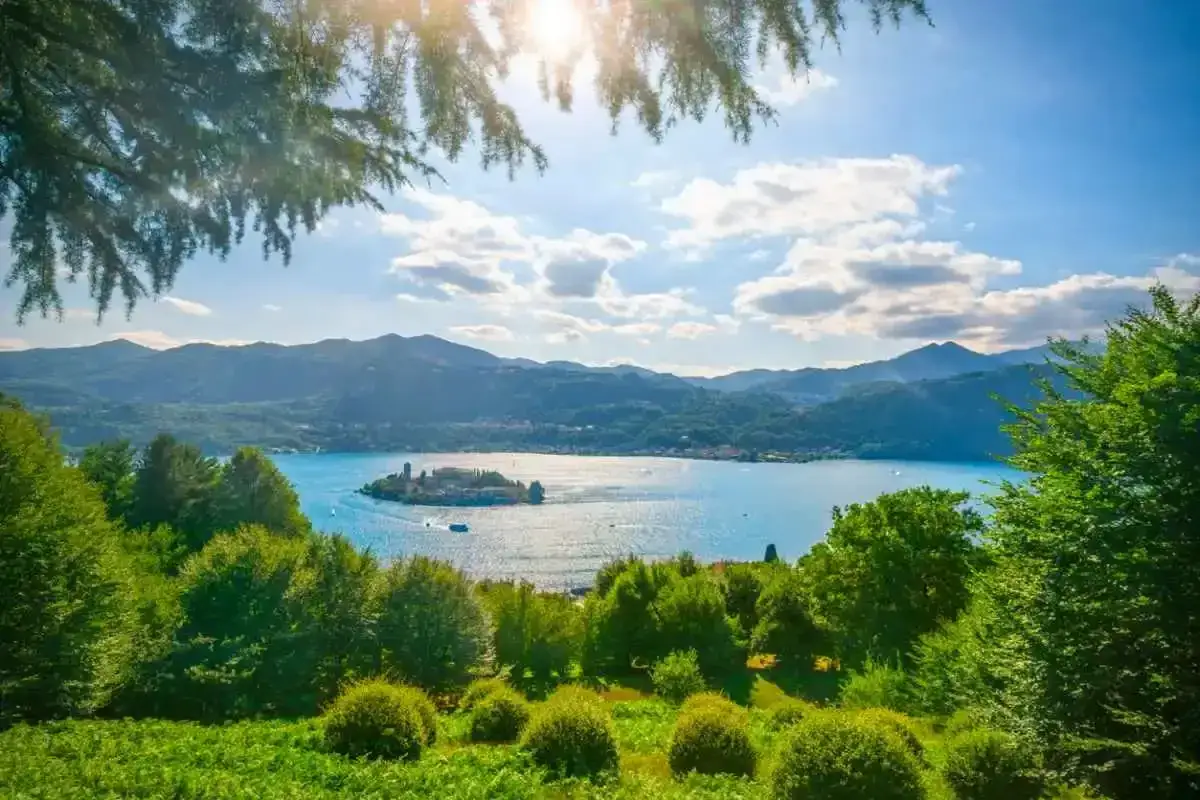 Un'isola con un palazzo si staglia su un lago azzurro, circondato da colline verdi. Un gioiello tra i laghi italiani.