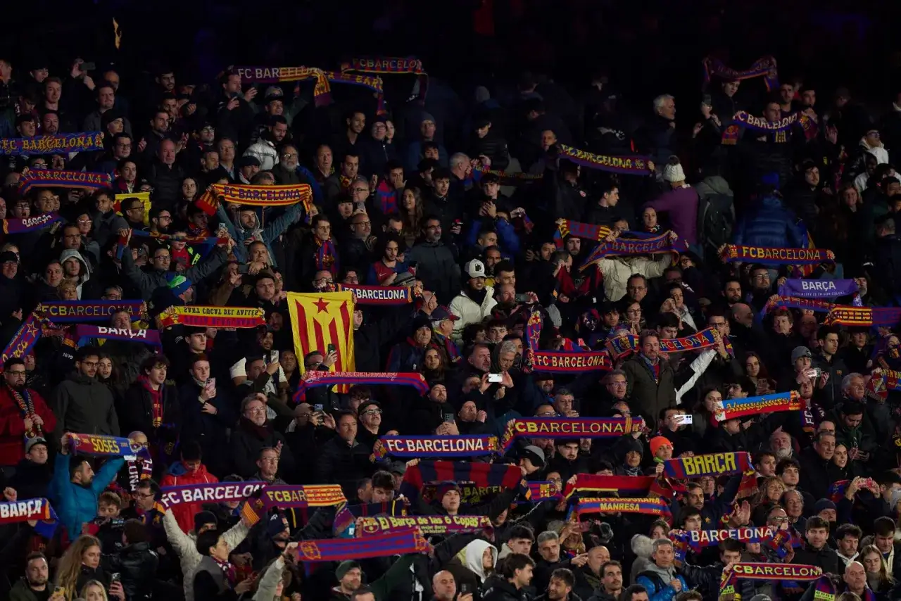 Tłum kibiców FC Barcelona, trzymających szaliki z napisem