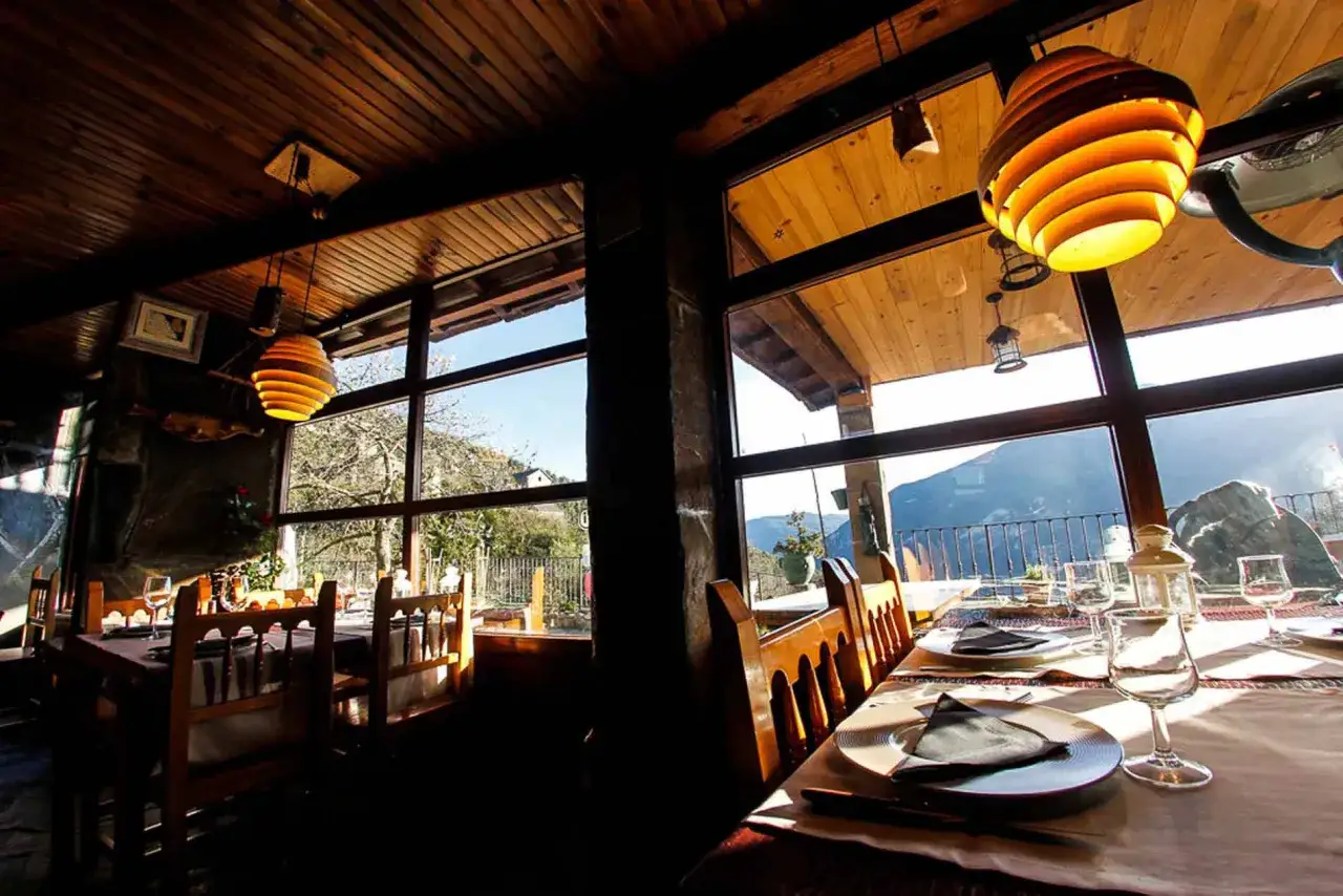 Mesas puestas con vistas a la montaña, ideal para saber donde comer en Broto. Ambiente rústico y acogedor.
