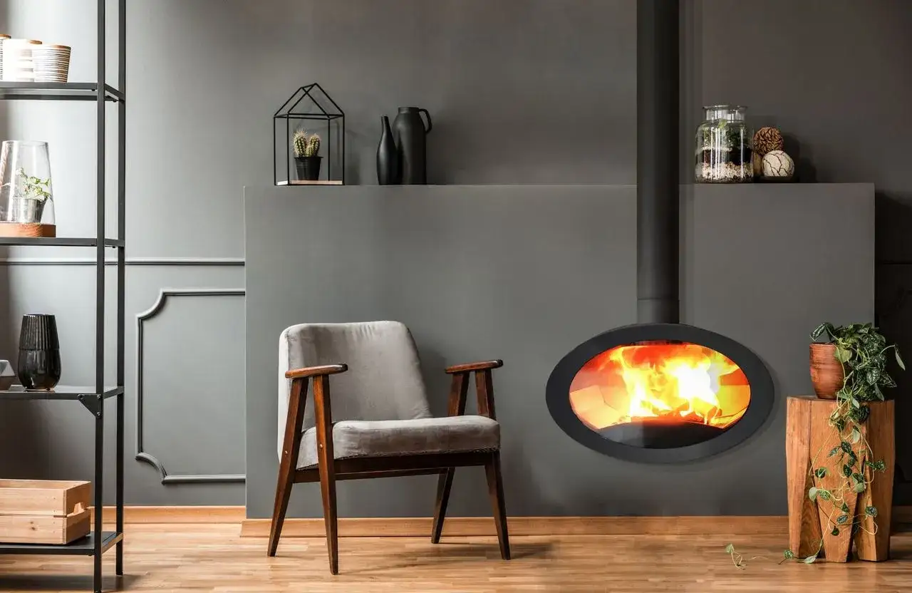 Un salon moderne avec un fauteuil vintage et un poêle à granulés convection naturelle ovale diffusant une douce chaleur.