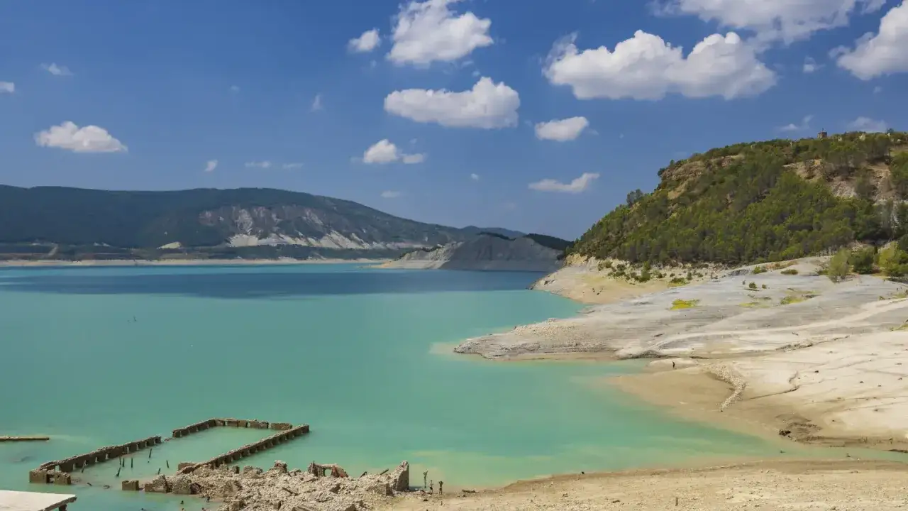 Paisaje de las termas de Yesa con aguas turquesas, montañas y ruinas sumergidas.