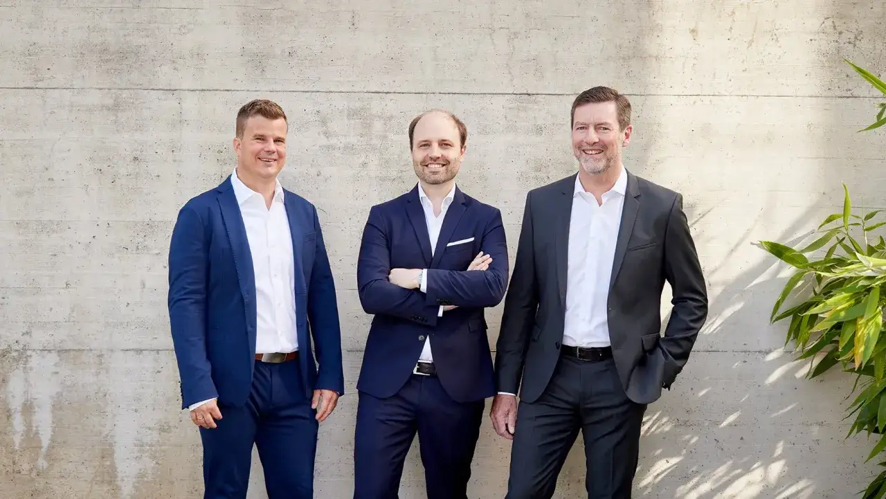 Drei Männer in Anzügen stehen vor einer Betonwand. Sie sind bereit, als Berater zu werden und ihre Expertise zu teilen.
