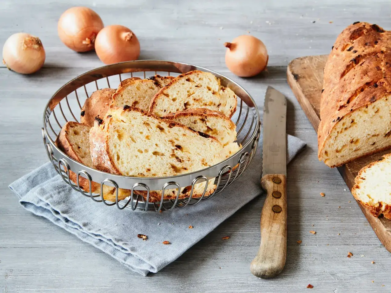 Frisch gebackenes Zwiebelbrot, bereit f&uuml;r ein leckeres Zwiebelbrot Rezept. Ganze Zwiebeln liegen daneben.