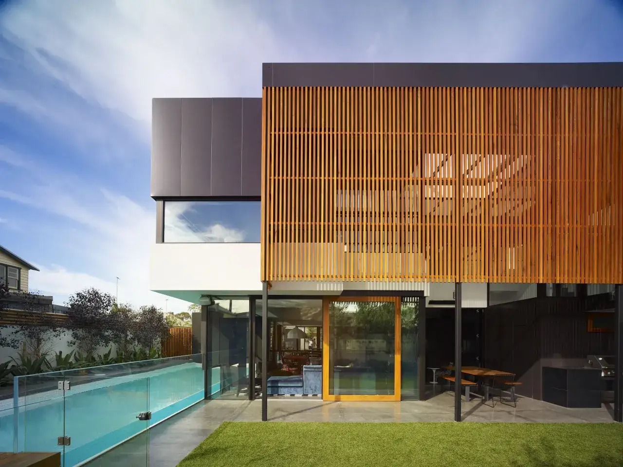 Moderne fenstergestaltung mit Holzlamellen und Glasfronten, die einen Pool und Gartenbereich freigeben.