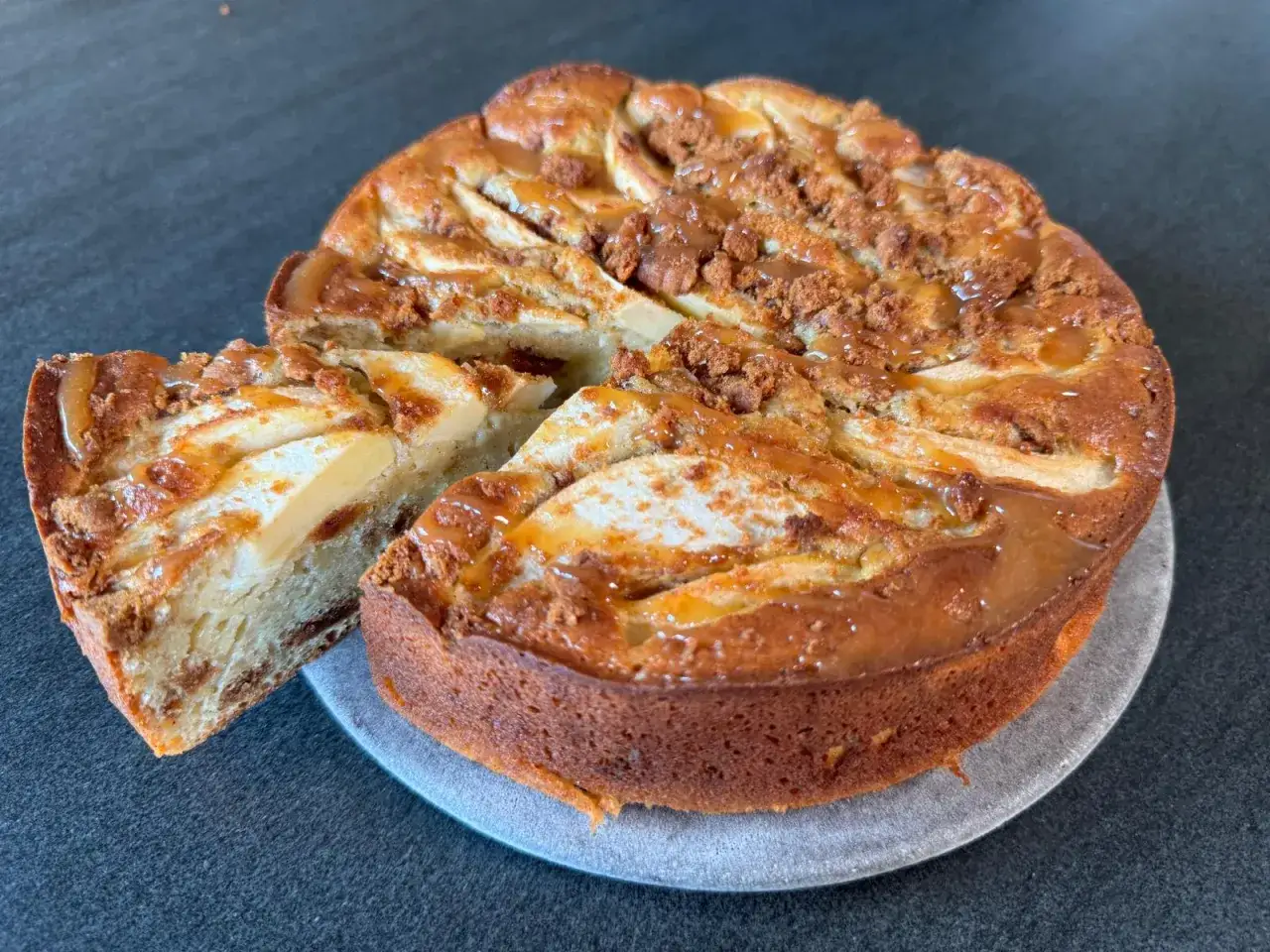 Gâteau pomme speculoos, une part coupée révèle la texture moelleuse et les morceaux de spéculoos.