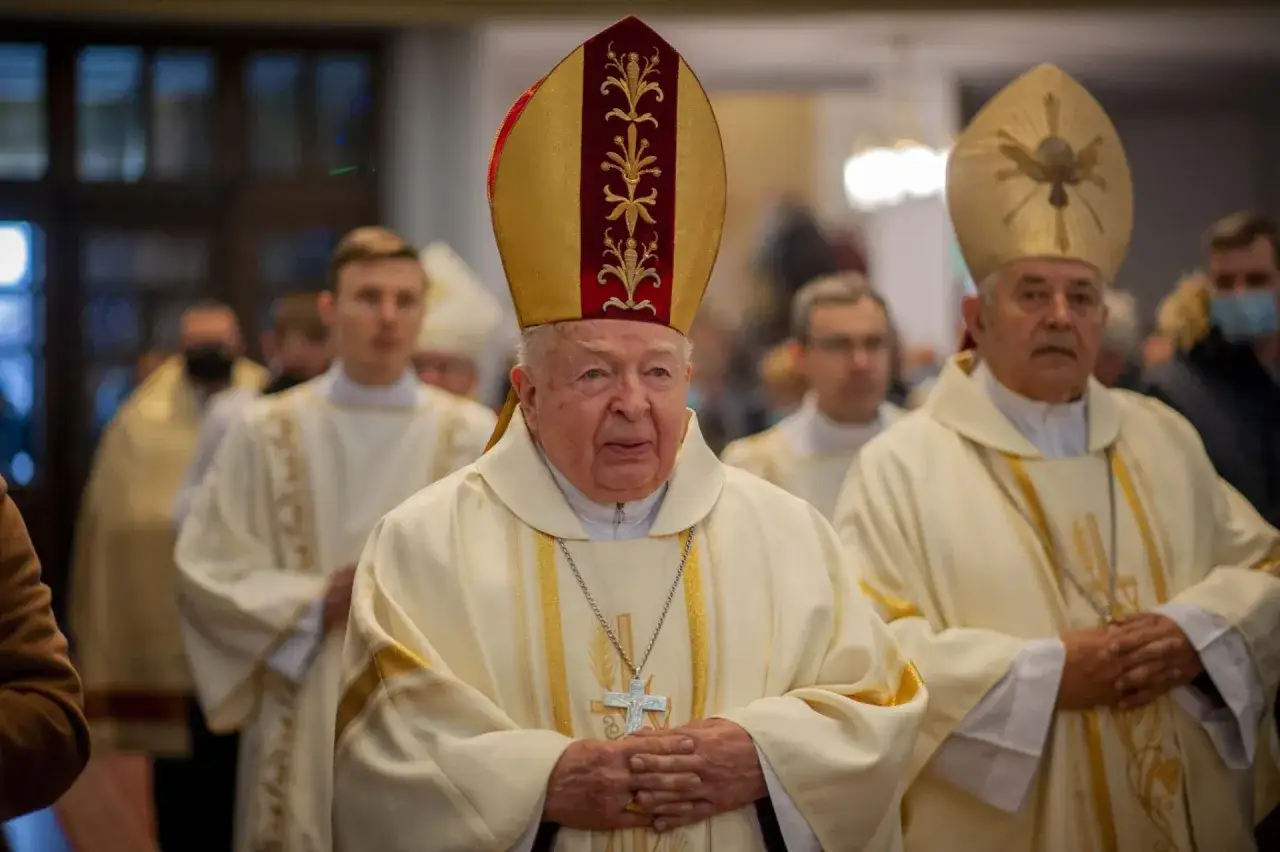 Uroczyste imieniny Kazimierza w kościele. Biskup w mitrze i szacie z krzyżem na szyi, otoczony przez innych duchownych.