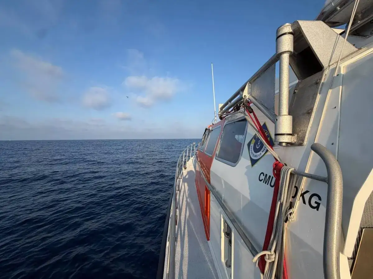 Bateau de sauvetage en mer, cherchant des personnes disparues en mer. L'océan est calme sous un ciel bleu.