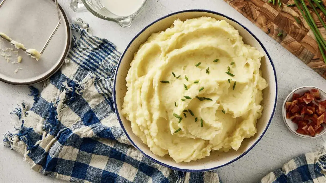 Un cremoso y apetitoso pure de patatas, adornado con cebollino fresco. Acompañado de tocino crujiente y un jarrito de leche.