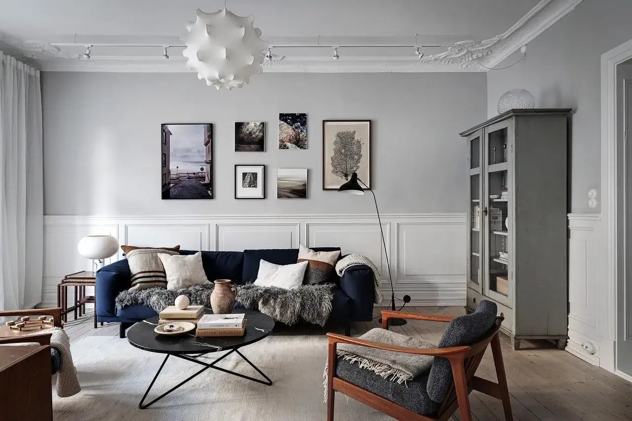 Granatowa ściana w salonie, przytulna sofa, stolik kawowy i fotel tworzą stylowe inspiracje.
