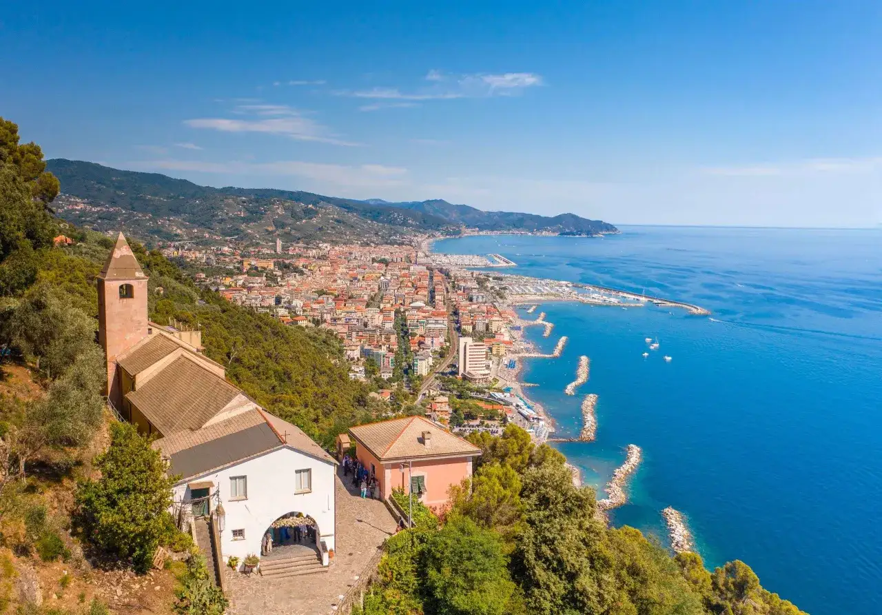 Vue aérienne de Chiavari, Italie. Une église et des maisons sur une colline surplombent la ville côtière et la mer d'un bleu profond.
