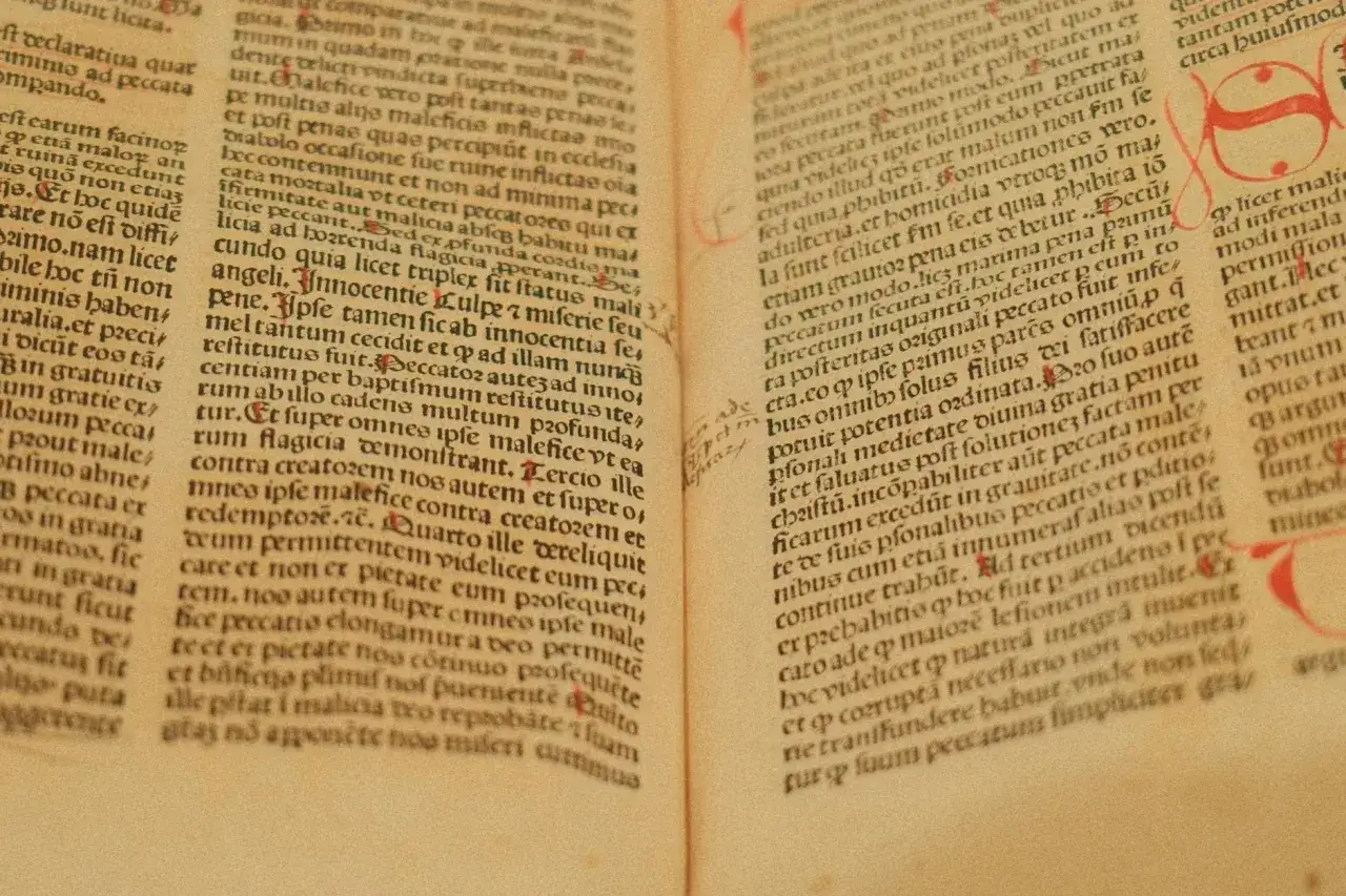 Stare manuskrypty z tekstem w języku łacińskim, litery i inicjały ozdobione czerwienią.