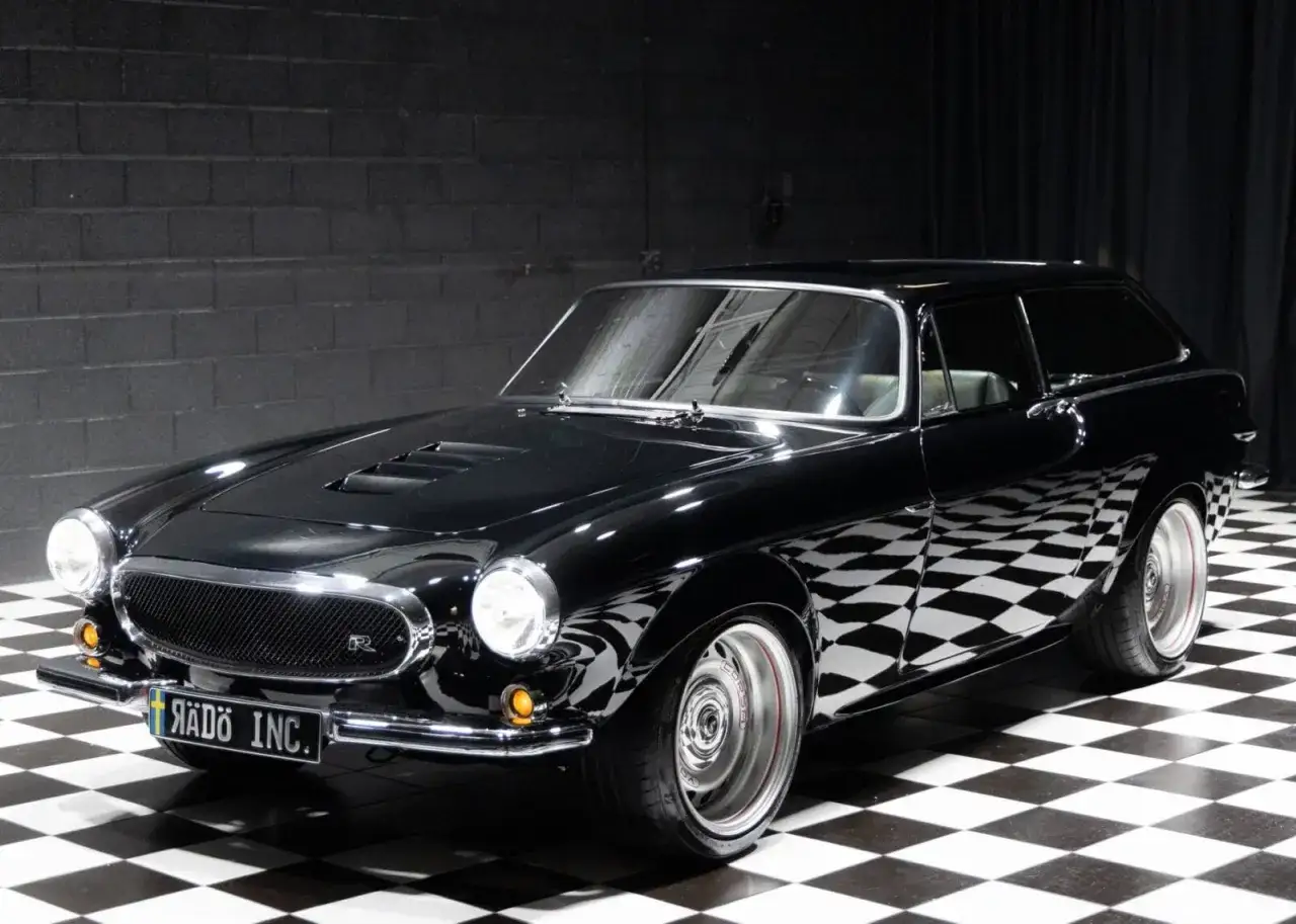 Schwarzer Volvo P1800 Shooting Brake mit Chromdetails und auffälligen Felgen auf kariertem Boden.