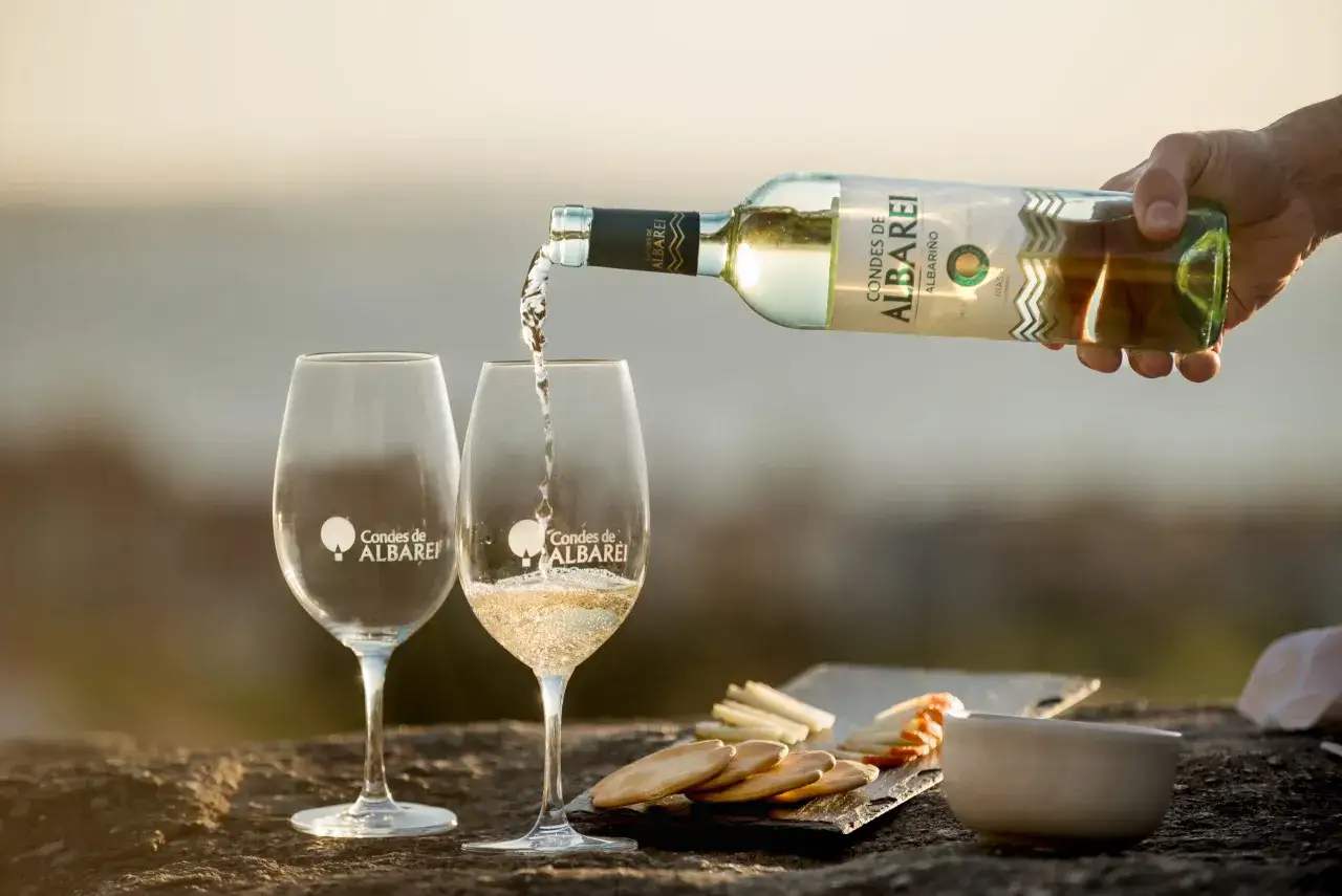 Vino blanco Albariño de Condes de Albarei, el mejor vino blanco de España, servido en copas con aperitivos.