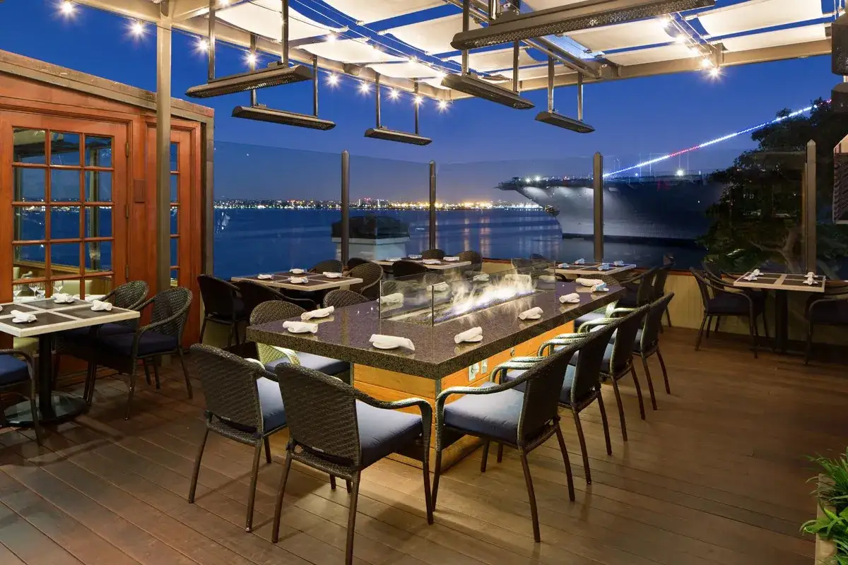 Terrazza con vista sul porto di San Diego, tavoli apparecchiati e un braciere centrale. Perfetto per scoprire i migliori posti dove mangiare a San Diego.