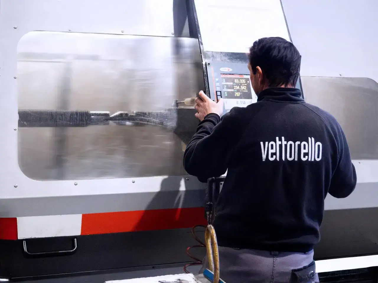 Operaio controlla un macchinario CNC, simbolo del cad cam significato nell'industria moderna.