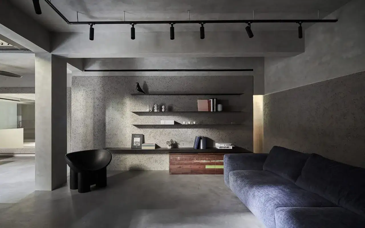 Arredare taverna con stile moderno: divano blu, poltrona nera scultorea, mensole minimaliste e illuminazione a faretti.