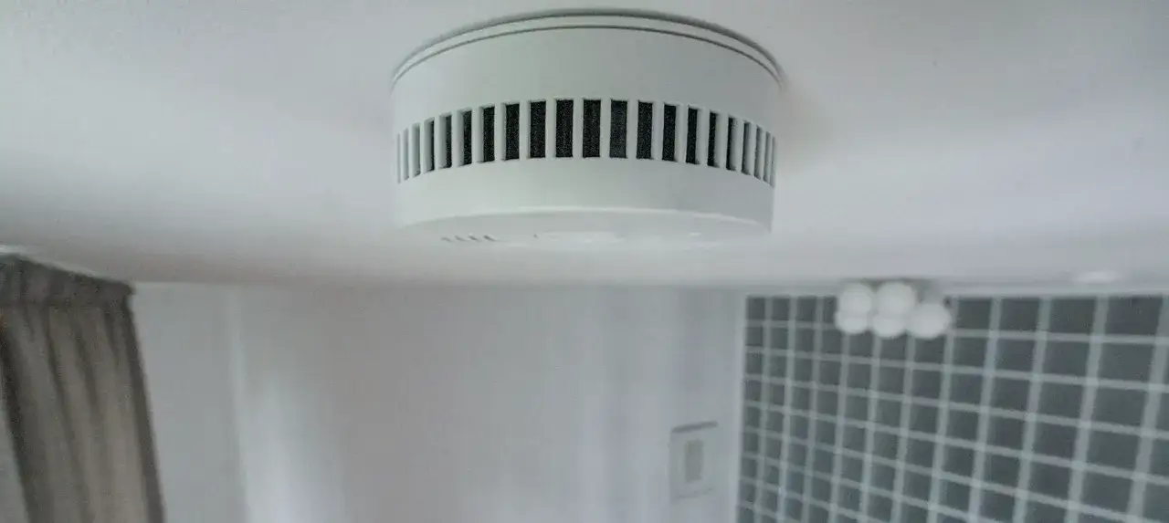 Ein weißer Rauchmelder an der Decke, der für Sicherheit in Hamburg sorgt.
