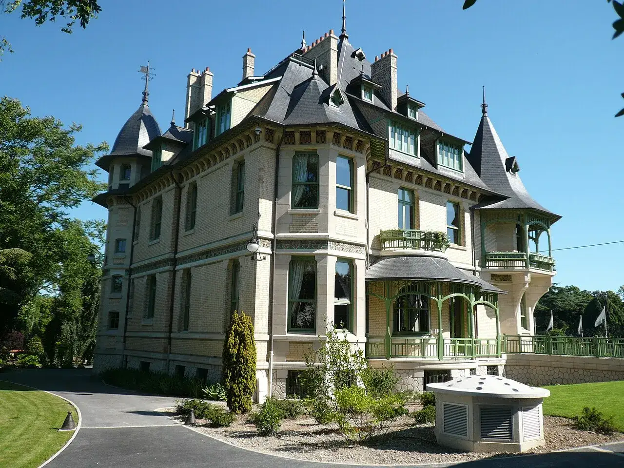 Magnifique maison demoiselle à Reims, avec ses tourelles, balcons verts et sa façade en briques claires. Un style architectural unique.