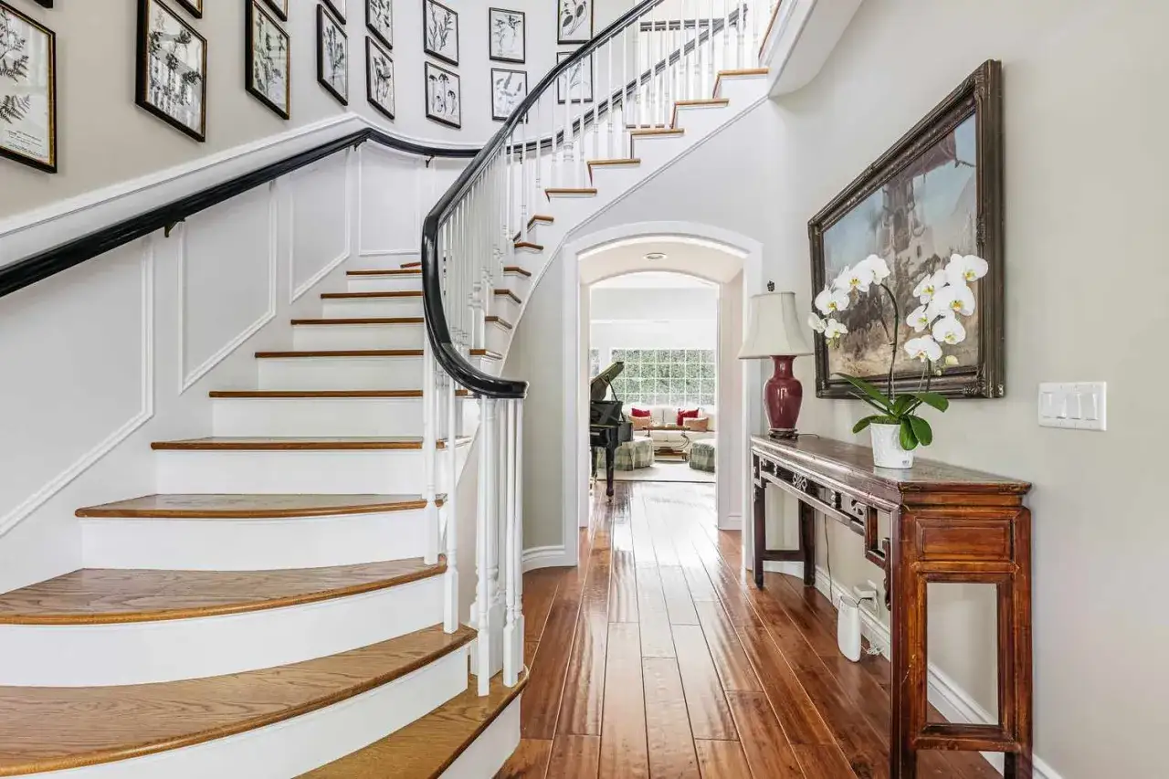 Elegant trappa inomhus inspiration med vit balustrad och m&ouml;rkt r&auml;cke. Konstverk pryder v&auml;ggen ovanf&ouml;r en antik konsol.