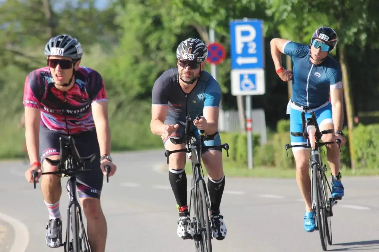 Trzech zawodników na rowerach podczas zawodów. To część ich kalendarza triathlonowego.