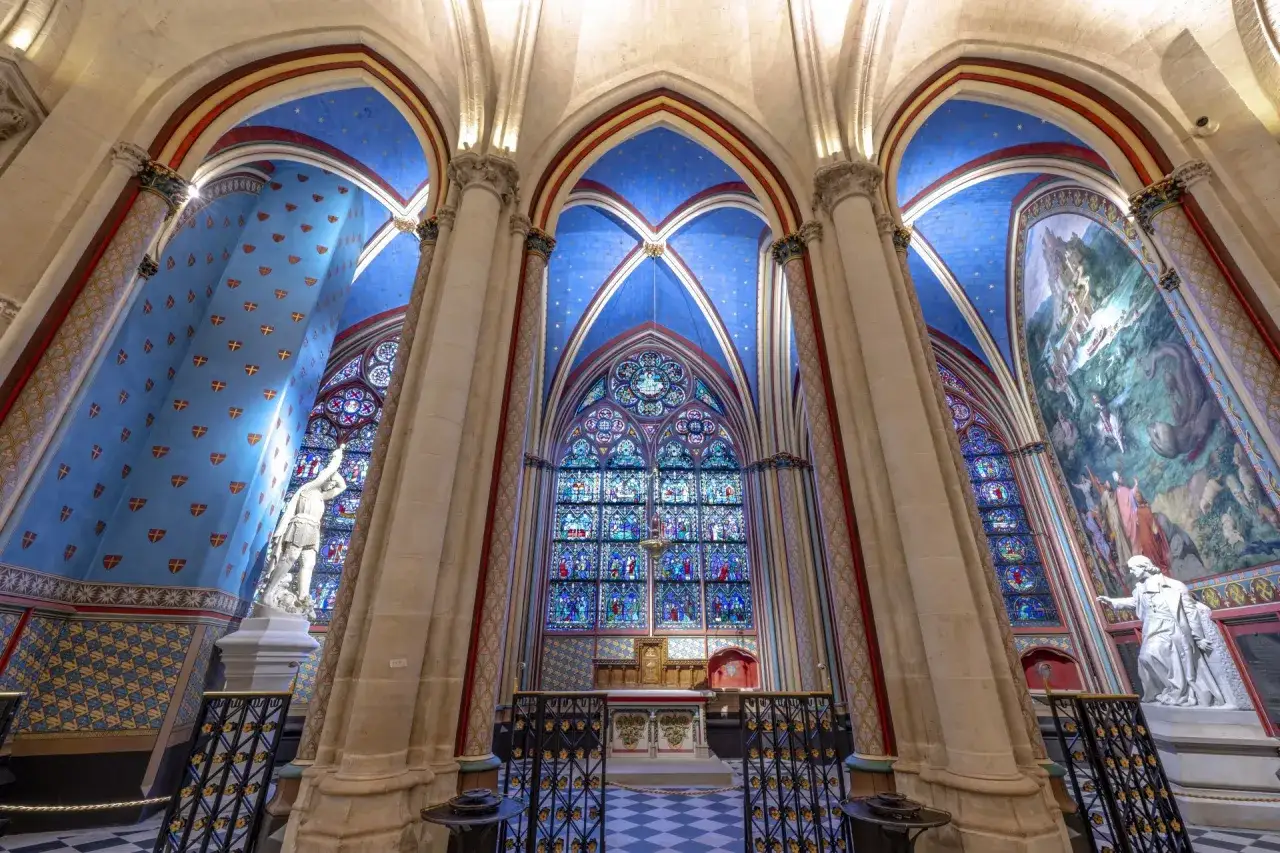 Interior de Notre Dame, con vitrales vibrantes, un fresco dramático y estatuas. Una visita inolvidable.