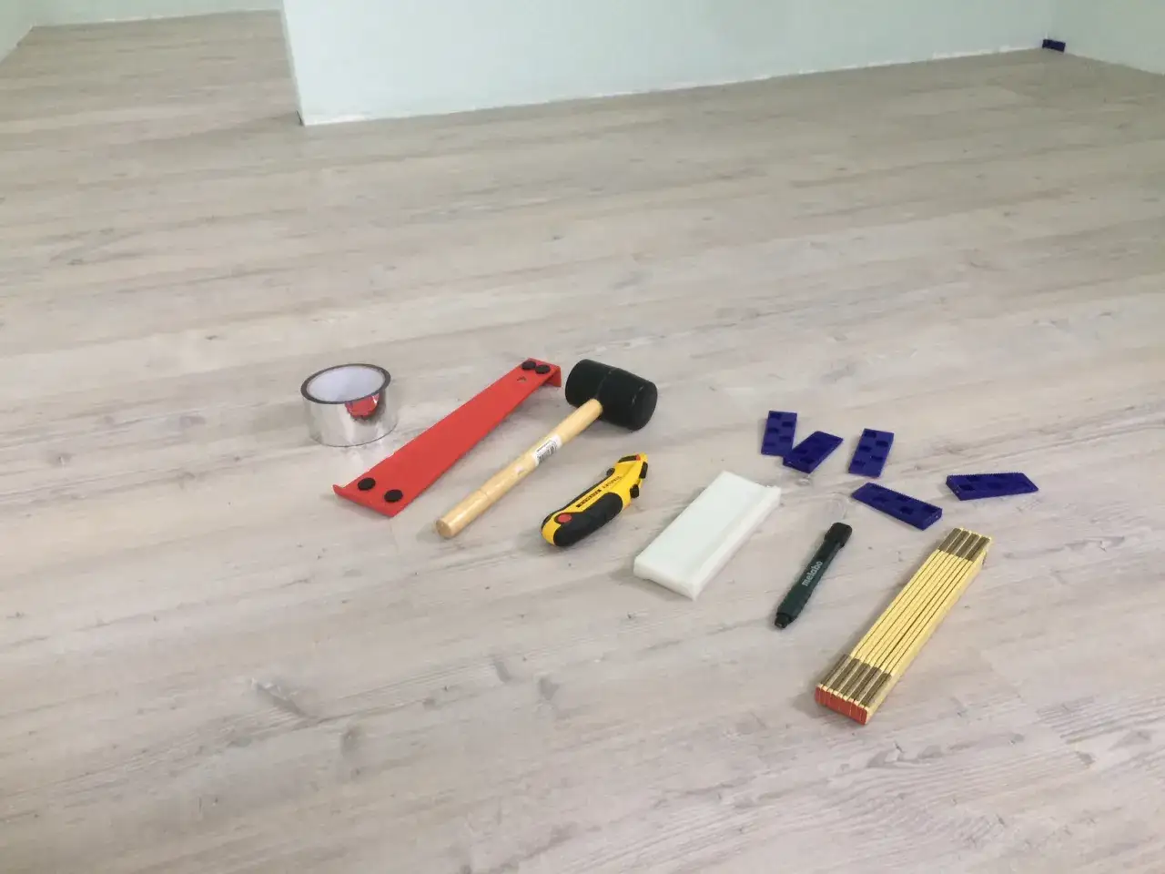 Werkzeuge f&uuml;r das Boden legen: Gummihammer, Cuttermesser, Distanzkeile, Ma&szlig;band und mehr liegen bereit.