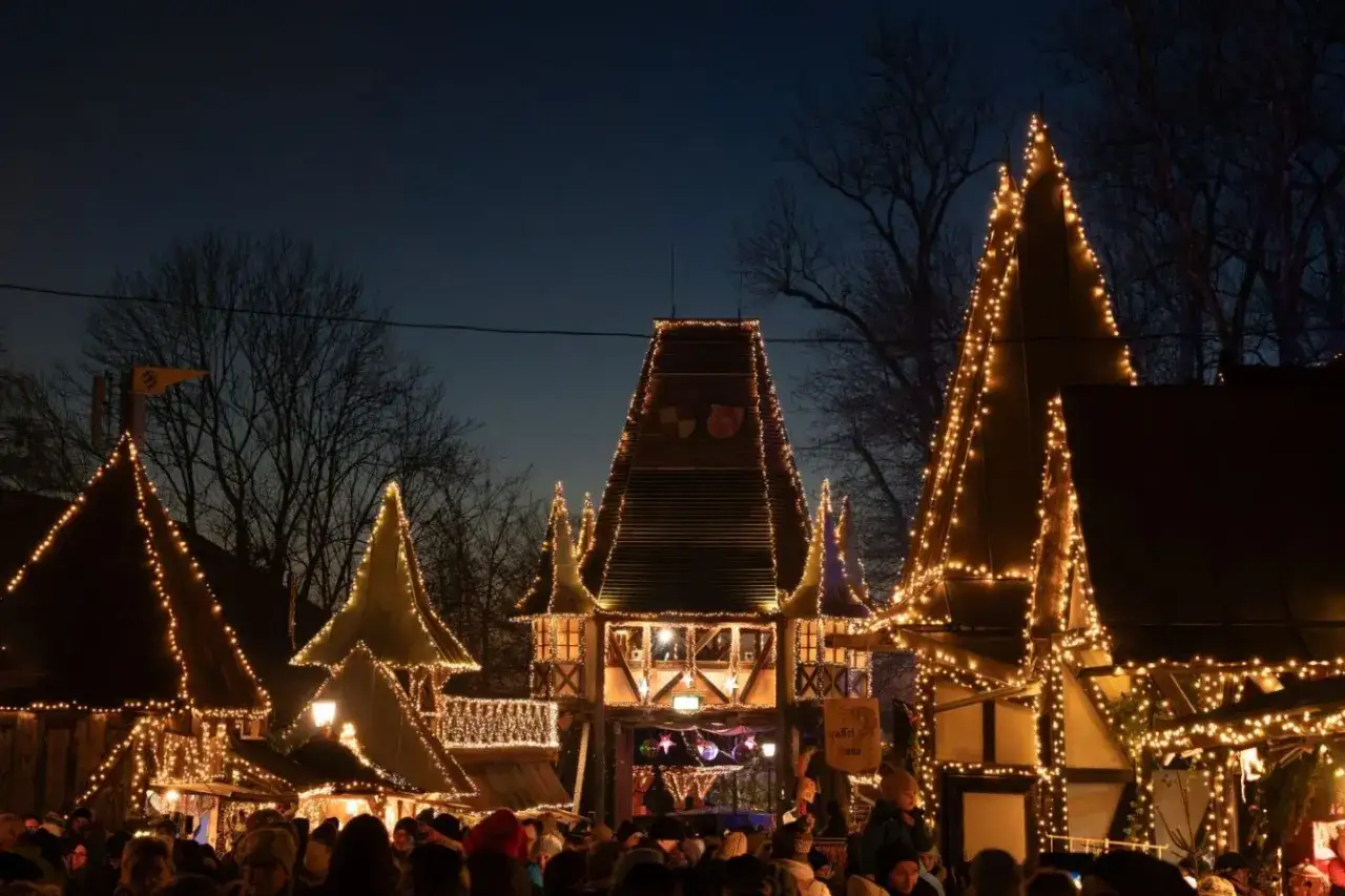 Der kleinste Weihnachtsmarkt der Stadt leuchtet im Dunkeln. Fachwerkh&auml;user mit spitzen D&auml;chern sind mit Lichterketten geschm&uuml;ckt, Menschen dr&auml;ngen sich auf dem Platz.