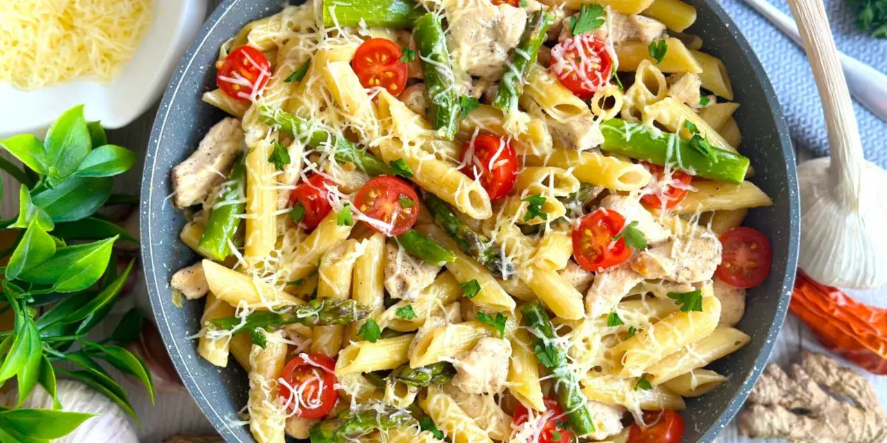 Penne z kurczakiem i szparagami w kremowym sosie, posypane parmezanem i pomidorkami koktajlowymi.