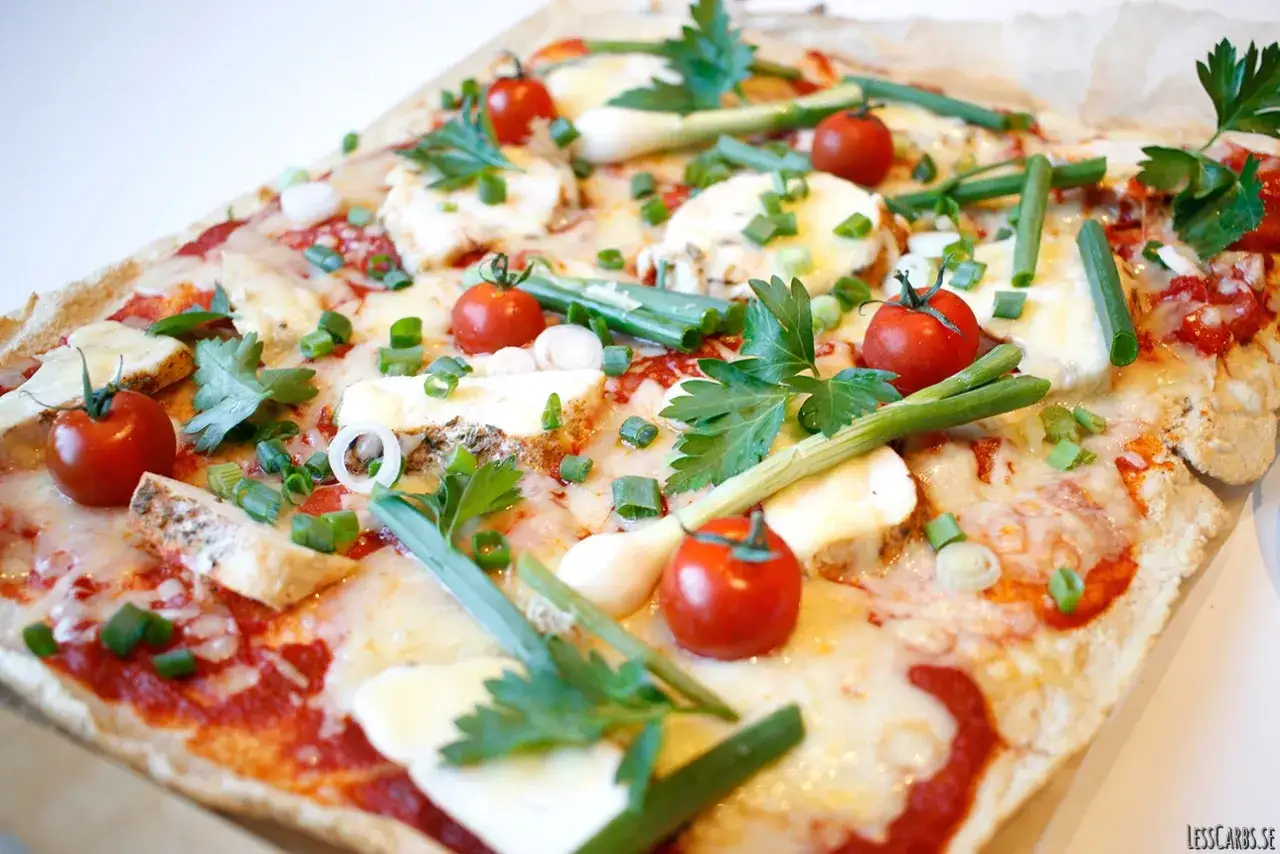 En läcker pizza med glutenfri pizzadeg recept, toppad med körsbärstomater, mozzarella och färska örter.