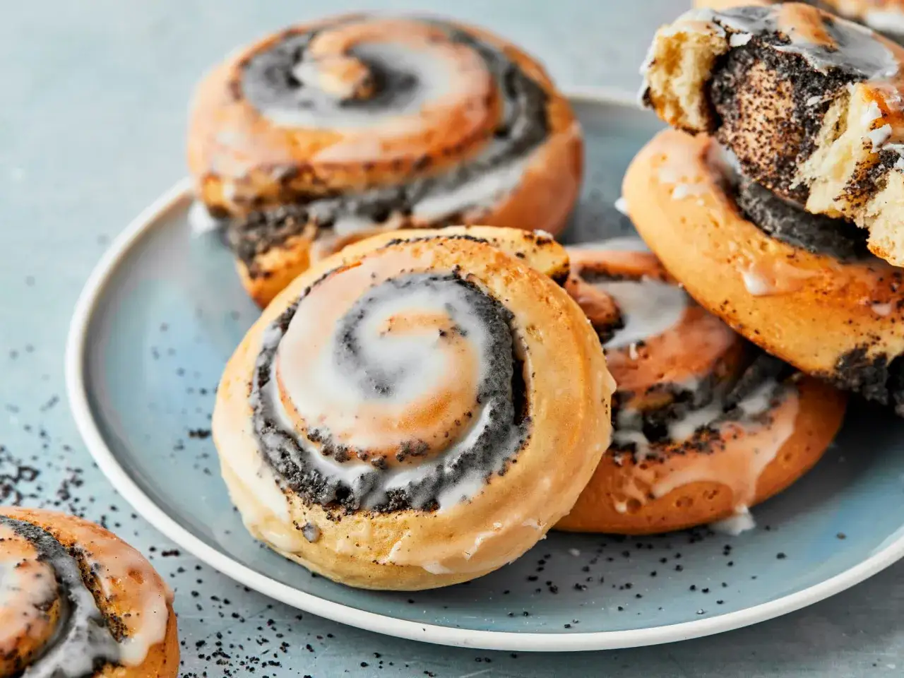 Saftige Mohnschnecken mit Zuckerguss auf einem blauen Teller. Dieses Mohnschnecken Rezept ist ein Genuss!