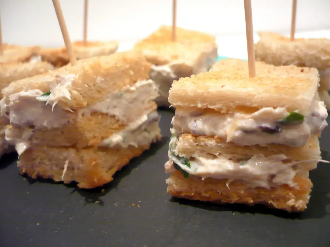 Petits sandwichs triangulaires garnis de rillettes de maquereau crémeuses, parfaits pour un apéritif.