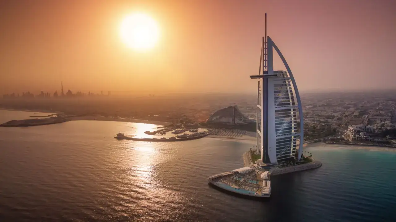 Zachód słońca nad Dubajem. Burj Al Arab, symbol luksusu, góruje nad wodą. Cena za noc w tym hotelu to marzenie wielu.