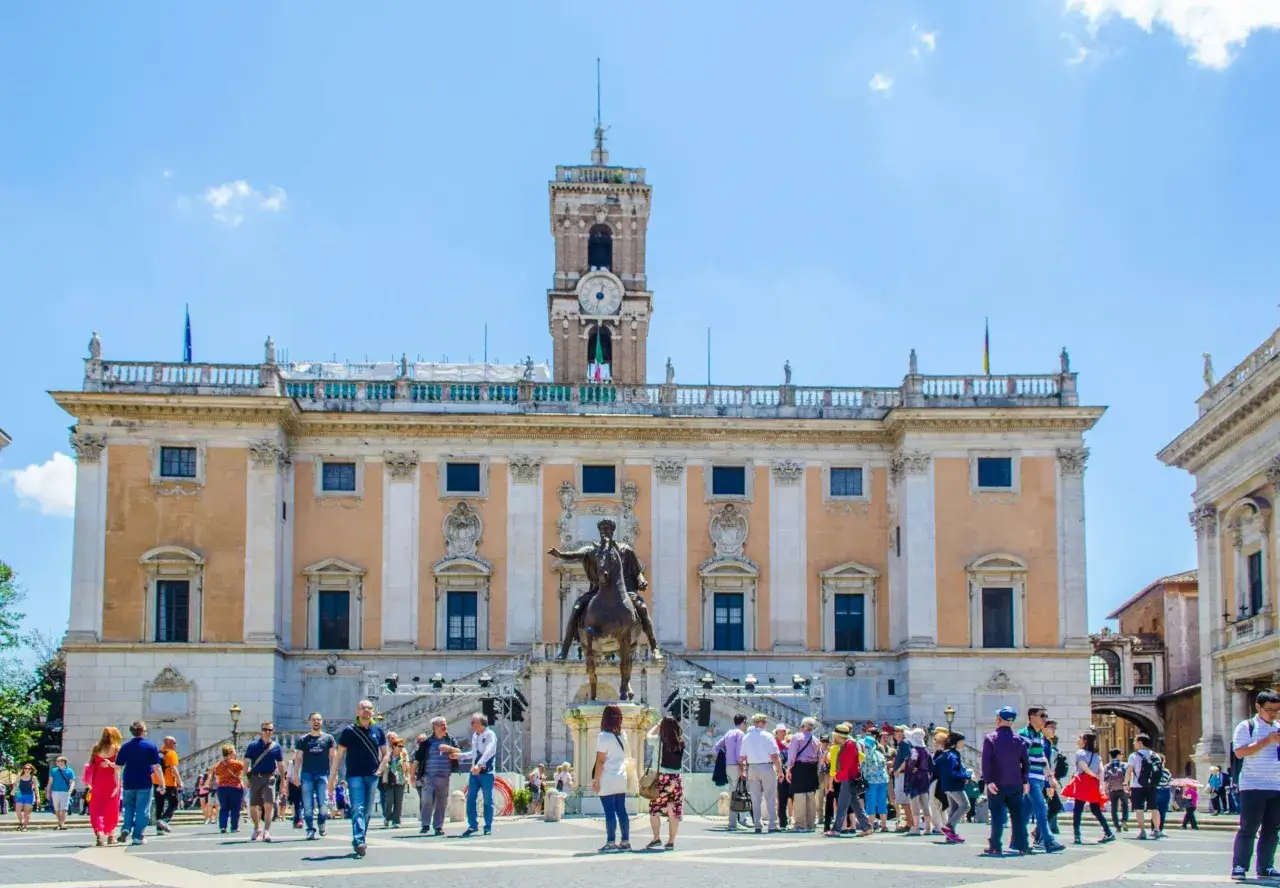 Tłum turystów na Piazza del Campidoglio w Rzymie. W tle Palazzo Senatorio. Bilety do Kapitol Rzym można kupić online.