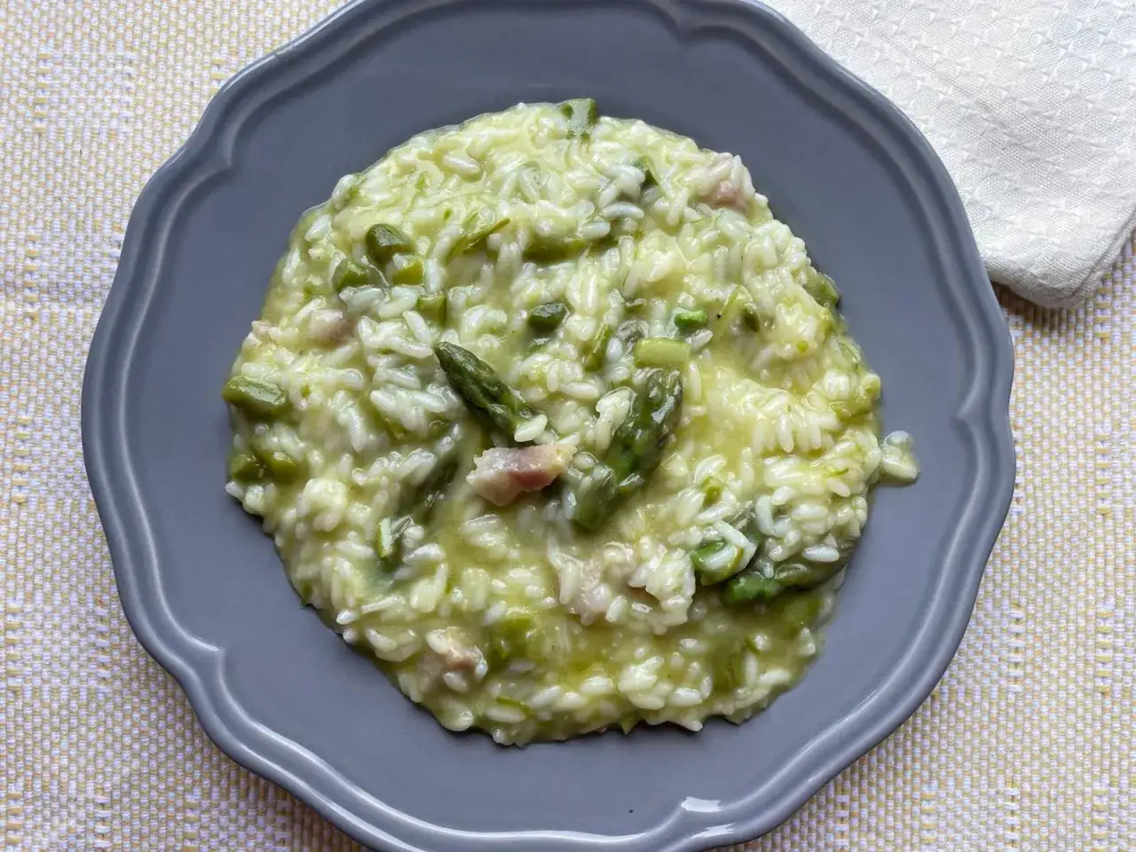 Un cremoso risotto con asparagi e pancetta, un piatto che profuma di primavera e tradizione.