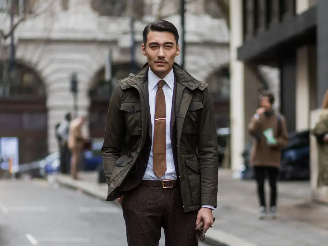 Hombre con ropa business casual: chaqueta verde, camisa blanca, corbata marrón y pantalones de tweed.