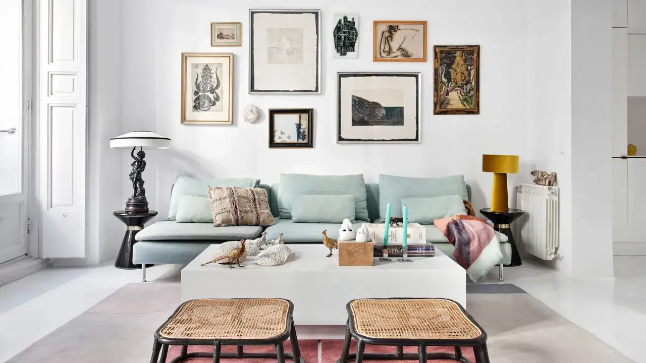Un sofá azul claro con cojines decorativos y una colección de arte en la pared. Ideas de **que poner detras del sofa** para un estilo ecléctico.